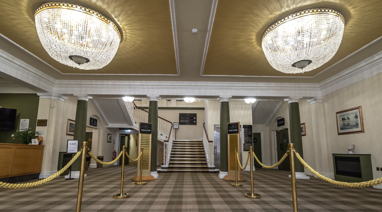 Entrance of Newcastle Racecourse featuring twin crystal chandeliers, central staircase, and classic columns