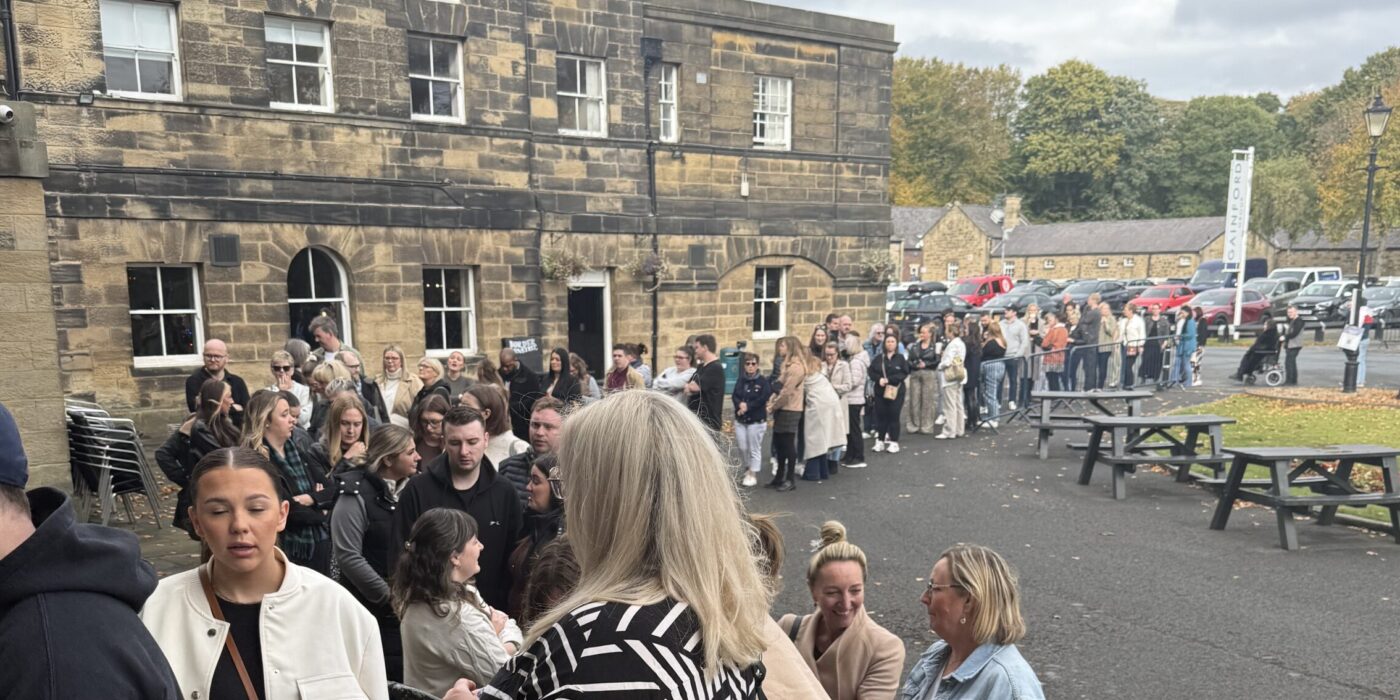 Long queue of excited couples and wedding planners stretching around building entrance, waiting to enter wedding fair