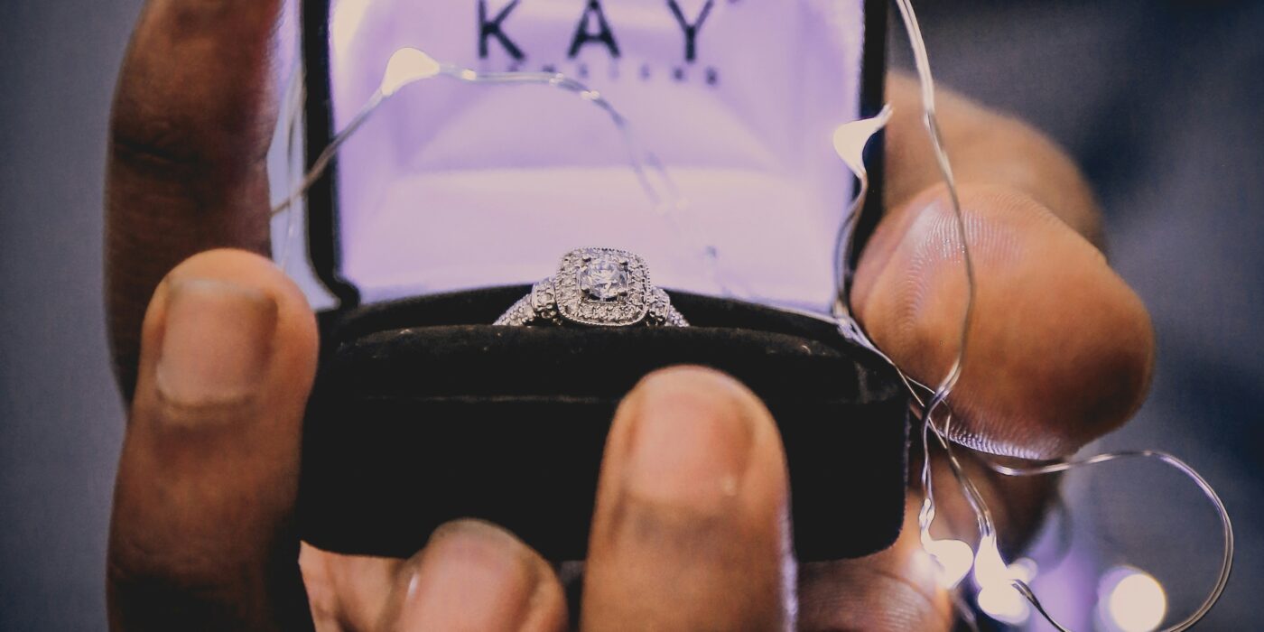 hand, holding black ring box, wedding ring inside.
